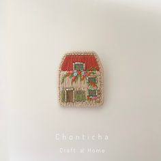 a small woven patch with a red house on the front and green shutters in the back