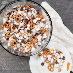 a glass bowl filled with marshmallows and pretzels on top of a white plate