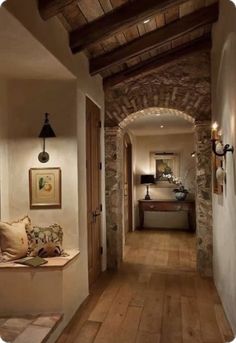 a long hallway with stone walls and wooden flooring is lit by two wall sconces