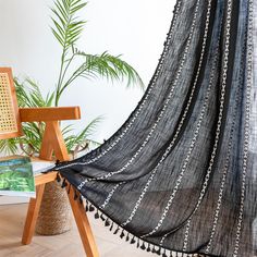 a black and white blanket sitting on top of a wooden chair next to a potted plant