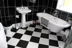 black and white bathroom with checkered floor, claw foot bathtub, pedestal sink