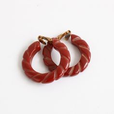 This wonderful pair of 1940's clip on hoop earrings, in deep red bakelite finished with carved details in a twisted rope design , are the perfect finishing touch for your outfit. Length: 1.4 inches Width: 1.4 inches Material: Bakelite, Brass Label: none Condition: In beautiful vintage condition, with general tarnishing to the brass features. This is in no way apparent when the earrings are being worn. Please refer to the photographs as these form part of the product description. 40s Accessories, 1940s Earrings, Fashion Eras, 1950s Earrings, Clip On Hoop Earrings, 1940s Jewelry, Bakelite Jewelry, Red Accessories, Vintage Bakelite