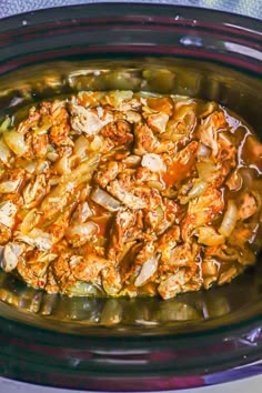 a crock pot filled with meat and vegetables on top of a blue table cloth