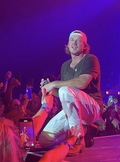 a man is sitting on the ground in front of a crowd with his cell phone