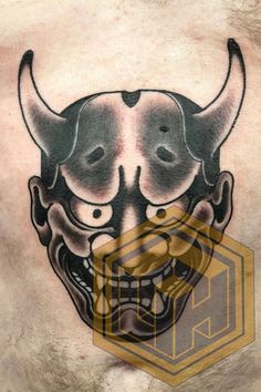 a man's chest with an image of a demon mask on it and the word,