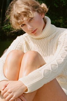 a woman in white sweater sitting on the ground