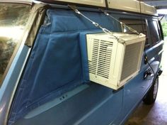 an air conditioner attached to the side of a blue car with a chain hanging from it's roof