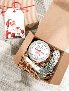 an open christmas gift box with a santa clause on it and a small tag hanging from the top