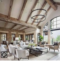 a living room filled with lots of furniture next to large windows and a chandelier hanging from the ceiling