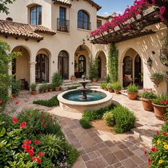 a fountain in the middle of a courtyard with potted plants and flowers around it