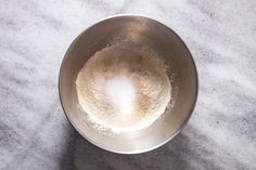 a metal bowl filled with flour on top of a counter