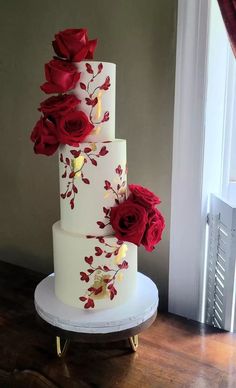 a three tiered white cake with red flowers on it