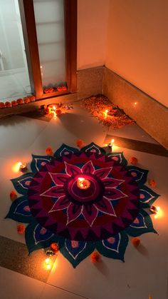 candles are lit on the floor in front of a large flower