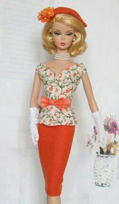 a barbie doll wearing an orange dress and hat with flowers on it's head