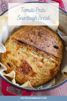 a baked bread in a pan with text overlay that reads tomato pesto sourdough bread