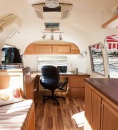 the interior of an rv with wood flooring and cabinets, desks, and chairs