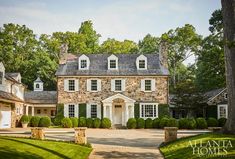 a large stone house surrounded by lush green trees