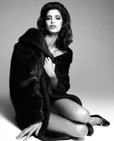 a woman sitting on the ground wearing a fur coat