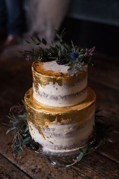 a three tiered cake sitting on top of a wooden table next to a person