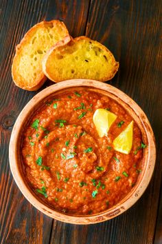 a bowl of red sauce with bread on the side