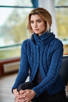 a woman sitting on a chair wearing a blue sweater