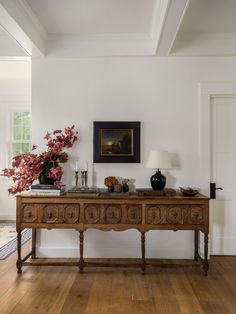 a wooden table with two vases on top of it in front of a painting