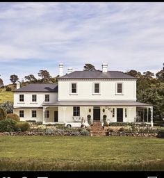 a large white house sitting on top of a lush green field