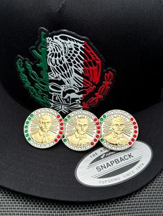 three different colored coins sitting on top of a black hat with a red, white and green eagle patch