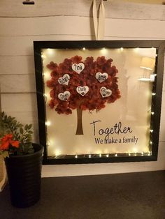 a framed family tree with lights in the shape of hearts and words that spell out together