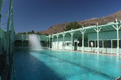 an empty swimming pool with water shooting up from it's sides and mountains in the background