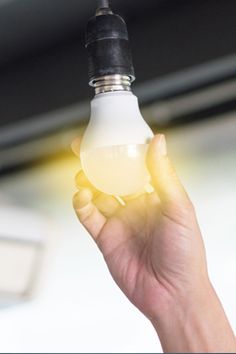 a person holding a light bulb in their left hand with the light shining on them