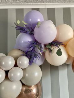 balloons and greenery are arranged on the wall in front of a striped wallpaper