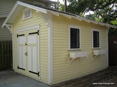 a small yellow shed with two windows on the side