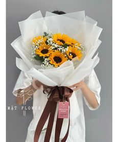 a woman holding a bouquet of sunflowers in her hands