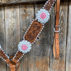 a horse bridle with pink flowers and white daisies on brown leather straps