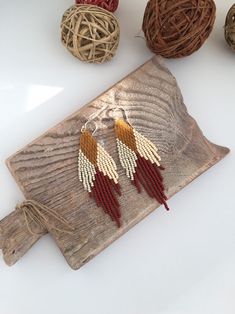 two pairs of red and white beaded earrings sitting on top of a piece of wood