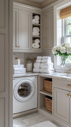 a washer and dryer in a bathroom with lots of towels on the shelves