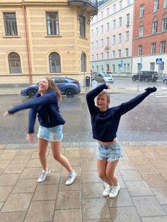 two young women are dancing in the rain