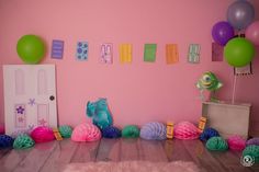 a room with pink walls and decorations on the floor, along with colorful balloons in the air