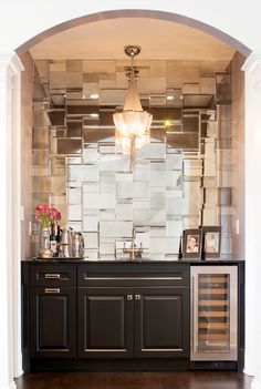 a wine cooler in the middle of a room with a chandelier above it