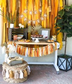 an orange and yellow birthday party with tassels on the table, food and decorations