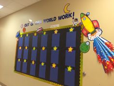 the bulletin board is decorated with rockets and stars on it's sides, along with an out of this world work sign