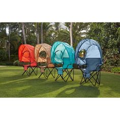 four different colored chairs sitting in the grass