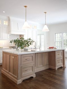 a large kitchen with an island in the middle and two lights hanging from the ceiling