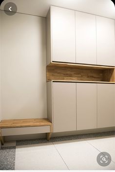 an empty room with white cupboards and a wooden bench