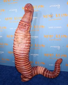 a very strange looking animal made out of wood on a blue carpet in front of a wall