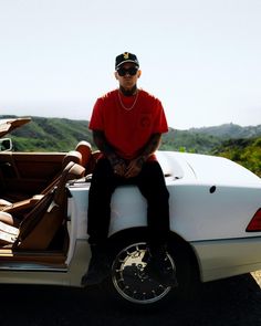 a man sitting on the back of a white car