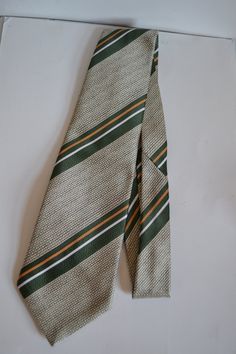 Vintage 1970s Andre Jacques Mens Polyester Necktie  A neat 1970s British mens necktie from the British brand, Andre Jacques. The necktie is 131cm long, 10cm at its widest and 3cm at its narrowest. It is beige, military green, gold and light silver grey. The necktie is made of polyester. Made in Britain in 1979.  At your request, we offer free gift boxing tied in lovely satin or organza ribbon. Vintage Suit And Tie Accessories For Black Tie, Vintage Suit And Tie Accessories For Business, Vintage Black Tie Accessories, 1920s Ties Men, Vintage Ties For Black Tie Events, Vintage Ties For Men, Vintage Brown Ties For Formal Occasions, Vintage Brown Tie For Business, Vintage Business Tie