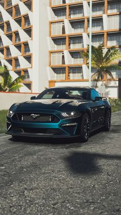 a blue sports car parked in front of a tall building