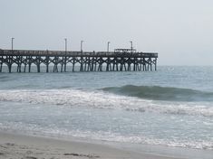 a pier on the beach with waves coming in